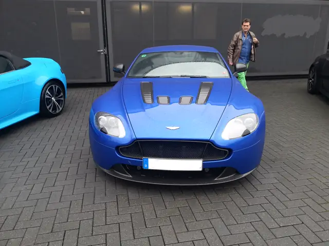 Blauer Aston Martin Vantage vor der Werkstatt