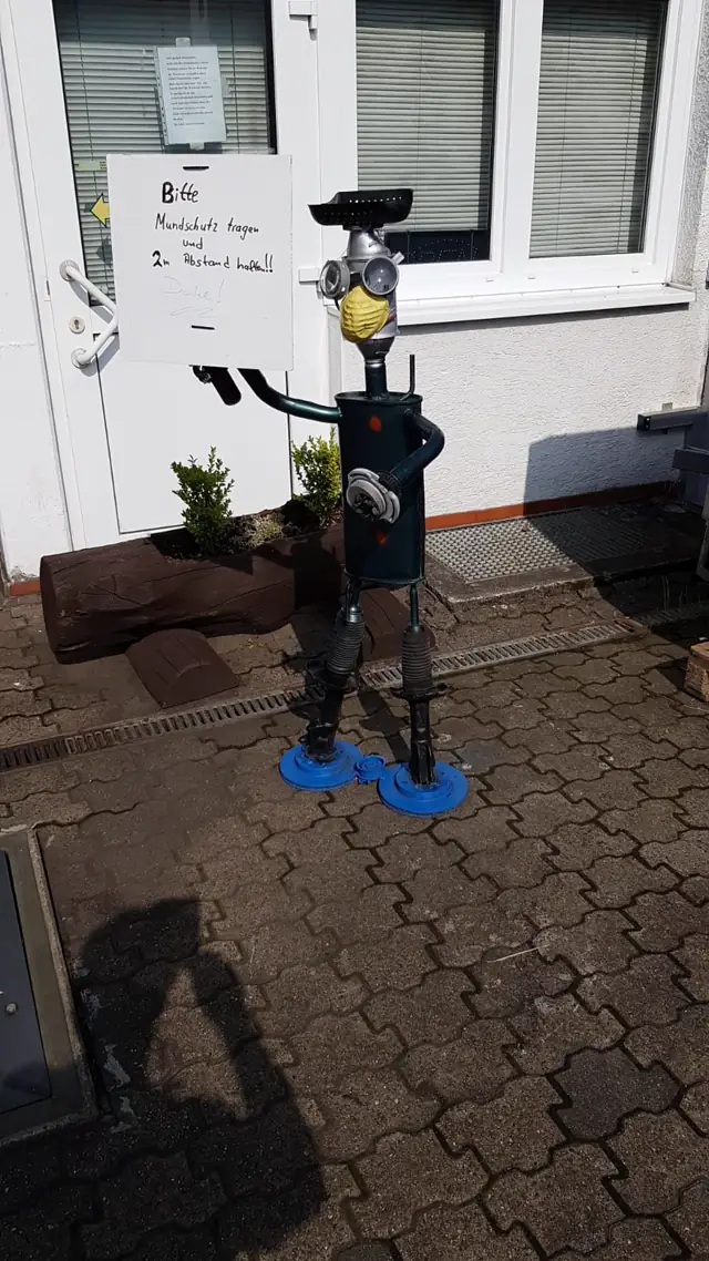 Figur mit Hinweisschild vor dem Eingang